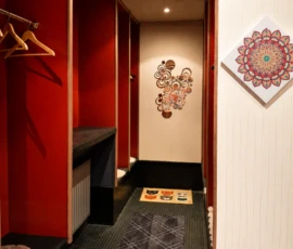 Umkleidebereich im Yogastudio mit roten Kabinen, Garderobe, Teppich und Mandala-Wandbild. Umkleidebereich im Yogastudio mit roten Kabinen, Garderobe, Teppich und Mandala-Wandbild.