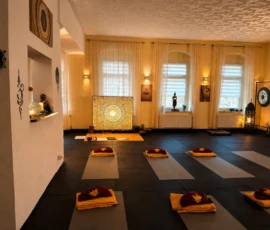 Yogaraum mit vorbereiteten Matten, Gong, warmem Licht und meditativer Fensterfront. Yogaraum mit vorbereiteten Matten, Gong, warmem Licht und meditativer Fensterfront.