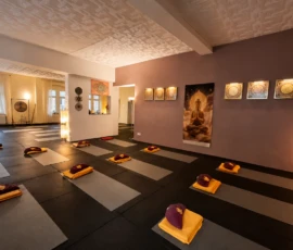 Vorbereiteter Yogaraum mit Matten, Meditationskissen, Leuchtelement und Fensterfront. Vorbereiteter Yogaraum mit Matten, Meditationskissen, Leuchtelement und Fensterfront.