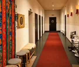 Flur des Yogastudios mit rotem Teppich, Sitzbereich, Wandkunst und warmer Beleuchtung. Flur des Yogastudios mit rotem Teppich, Sitzbereich, Wandkunst und warmer Beleuchtung.
